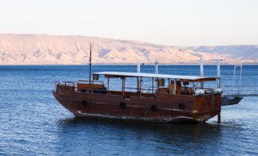"Group of pilgrims on a boat crossing the serene Sea of Galilee, reflecting on biblical stories associated with these waters.
