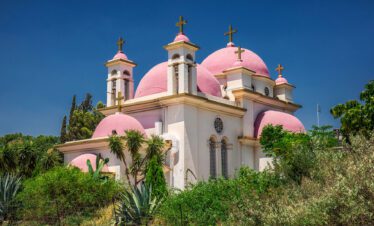 Visit Capernaum's ancient synagogue ruins on a Lionsgate Travel tour, where Jesus once preached, set against the scenic backdrop of the Sea of Galilee.