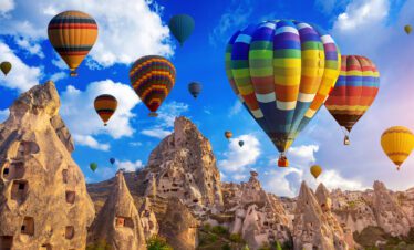 Colorful hot air balloons floating over the unique rocky landscapes of Cappadocia during early morning.