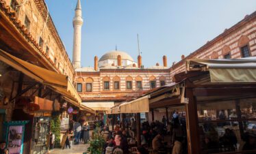 Vibrant scene from Izmir's lively market with stalls laden with colorful spices, textiles, and local handicrafts.