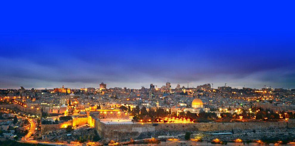 Panoramic view of Jerusalem showcasing the illuminated Dome of the Rock and the city's skyline at dusk, ideal for religious tours.